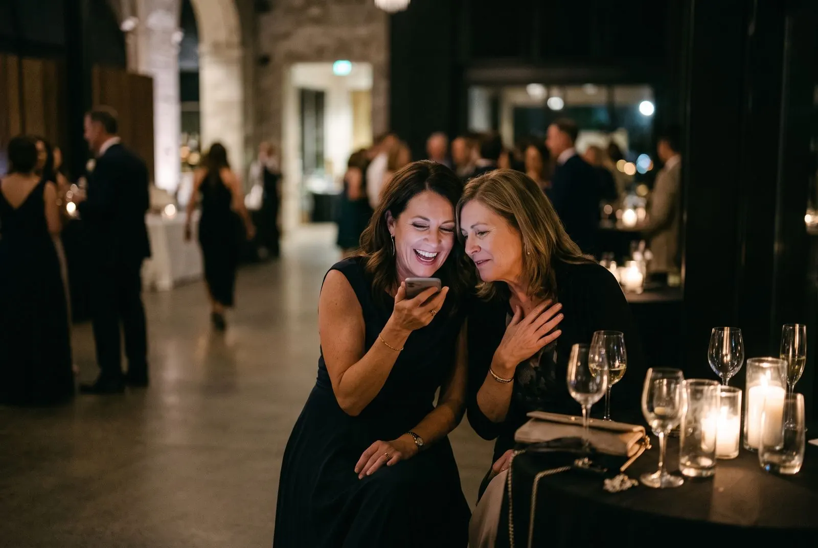 Two friends laugh as they record a voice message for the couple on a phone